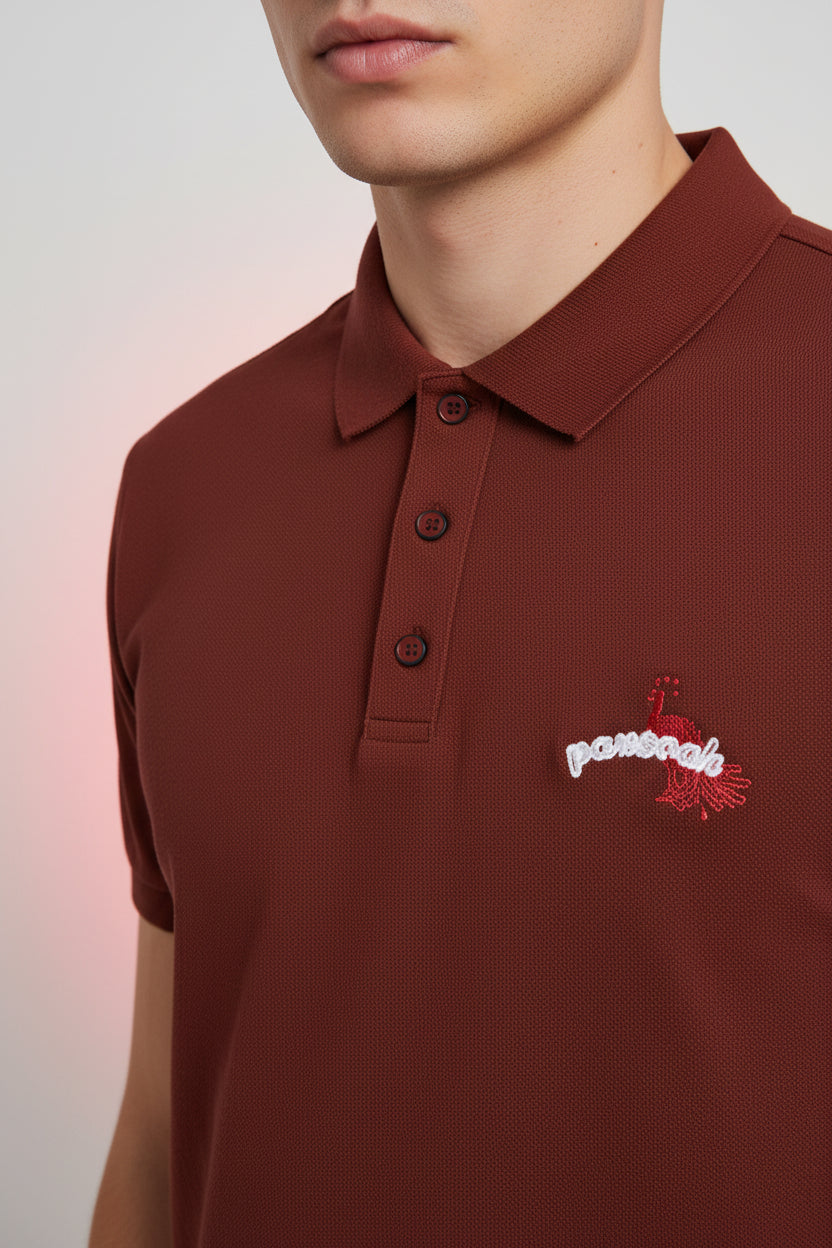 ZotRage brick red 100% cotton Airtex polo shirt with a structured collar and small white peacock chest embroidery.